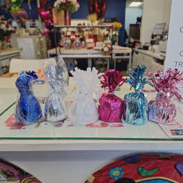 Foil-wrapped gift bags in blue, silver, white, pink, and teal on a counter