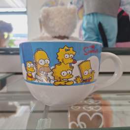 The Simpsons mug with a white handle on a glass shelf