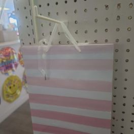 Pink and white striped gift bag hanging on a pegboard display