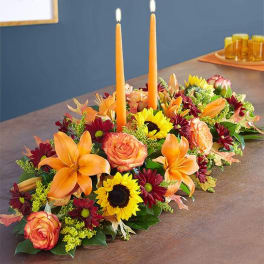 Long floral table centerpiece with orange candles and mixed blooms