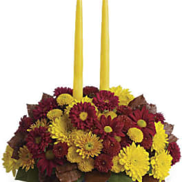 Yellow taper candles in a low arrangement of red and yellow mums