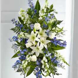 Standing floral spray with white lilies, white roses, and blue flowers