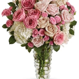 Pink and white roses arranged in a clear glass vase