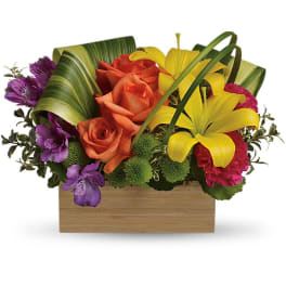 Colorful floral arrangement in a wooden box with roses and lilies