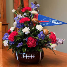Football-themed flower arrangement in a football-shaped vase with a Buffalo Bills pennant
