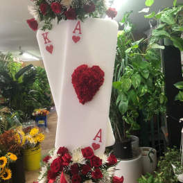 Tall floral arrangement with red roses and white flowers on a white display stand