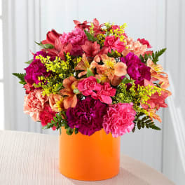 Bright mixed bouquet in an orange cylindrical vase