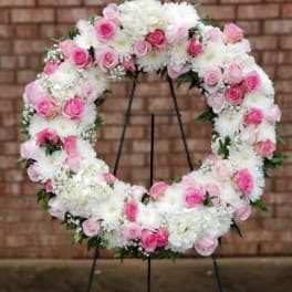 Pink and white floral wreath on a black stand