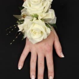 White rose wrist corsage with ribbon on a hand