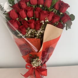 Bouquet of red roses wrapped in red and clear paper with a ribbon