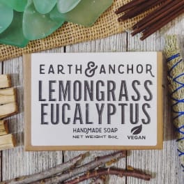 Handmade lemongrass eucalyptus soap bar in kraft packaging on a rustic wood surface.