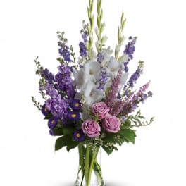 Tall bouquet of purple and white flowers in a clear glass vase