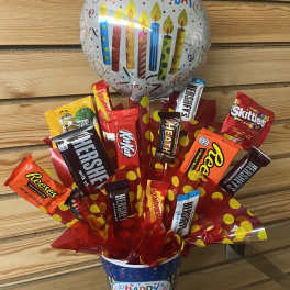 Birthday candy bouquet in a festive cup with assorted chocolate bars and a Happy Birthday balloon.