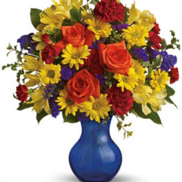Mixed bouquet of roses, daisies, and carnations in a blue vase