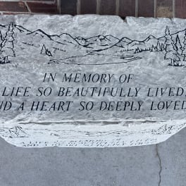 Engraved memorial stone with mountain and pine tree design