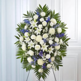 Standing funeral spray of white and blue flowers on an easel