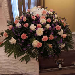 Large funeral casket spray with pink, white, and purple flowers
