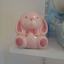 Pink ceramic bunny figurine with a bow sitting on a shelf