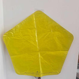 Yellow star-shaped foil balloon against a white wall