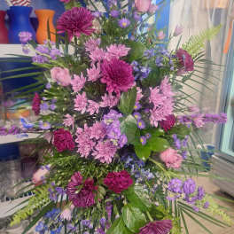 Tall bouquet of pink and purple flowers with palm fronds