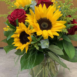 Bouquet of sunflowers and red roses in a glass vase
