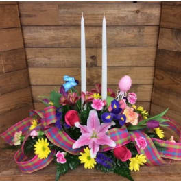 Colorful floral centerpiece with two white taper candles and a plaid ribbon