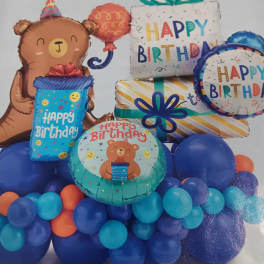 Birthday balloon arrangement with a teddy bear and gift balloons