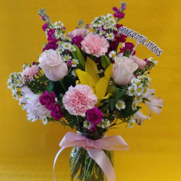 Pink and white mixed bouquet in a glass vase with a congratulations sign