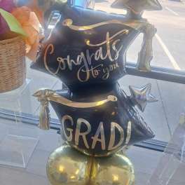 Black and gold graduation balloon display with star balloons and "Congrats to you GRAD!" text
