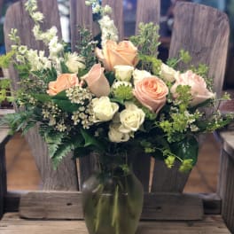 Peach and white roses in a green glass vase