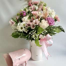 Pink and white mixed bouquet in a white vase with a pink ribbon