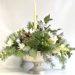 Pine and white floral centerpiece in a silver pedestal bowl with a tall candle