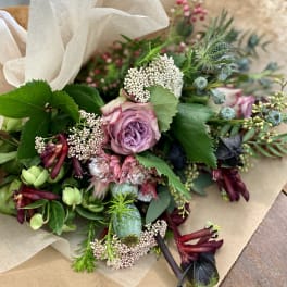 Bouquet of lavender roses with mixed blooms wrapped in brown paper