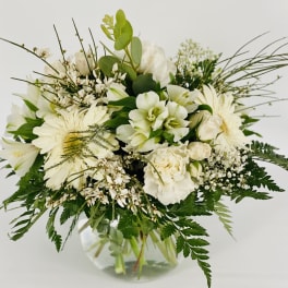 White floral bouquet in a clear glass vase with mixed greenery