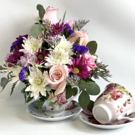Bouquet of pink, white, and purple flowers in a floral teacup and saucer
