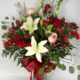 Bouquet of red and white flowers in a glass vase with a red ribbon
