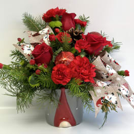 Red roses and carnations in a gray vase with holiday ribbon