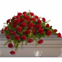 Red carnation casket spray arranged across a light gray casket