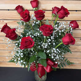 Red roses arranged in a glass vase with white baby's breath