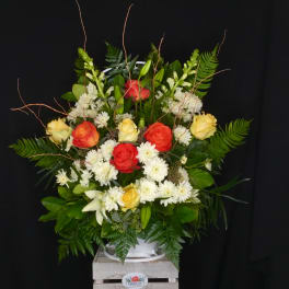 Large mixed bouquet of roses, lilies, and white daisies in a white container
