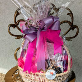 Gift basket wrapped in clear cellophane with pink and purple ribbon