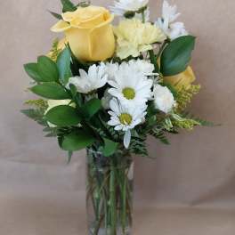 Yellow roses and white daisies in a clear glass vase