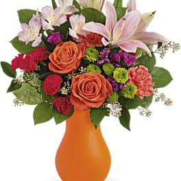 Mixed bouquet of roses, lilies, and carnations in an orange vase