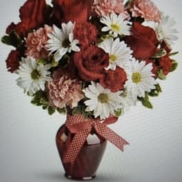 Red and white mixed flower bouquet in a burgundy vase with a ribbon