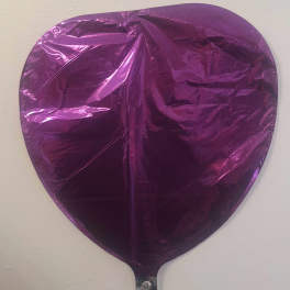 Purple heart-shaped foil balloon against a plain wall