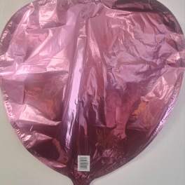 Pink metallic heart-shaped balloon against a plain wall
