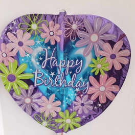Heart-shaped birthday balloon with colorful daisy graphics