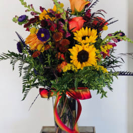 Colorful bouquet with sunflowers, roses, and a glass vase