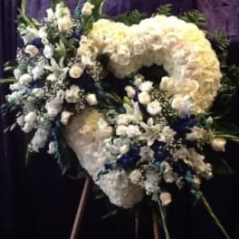 Large white floral funeral spray on an easel with blue accents