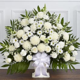 Large white floral arrangement in a vase with a white ribbon bow